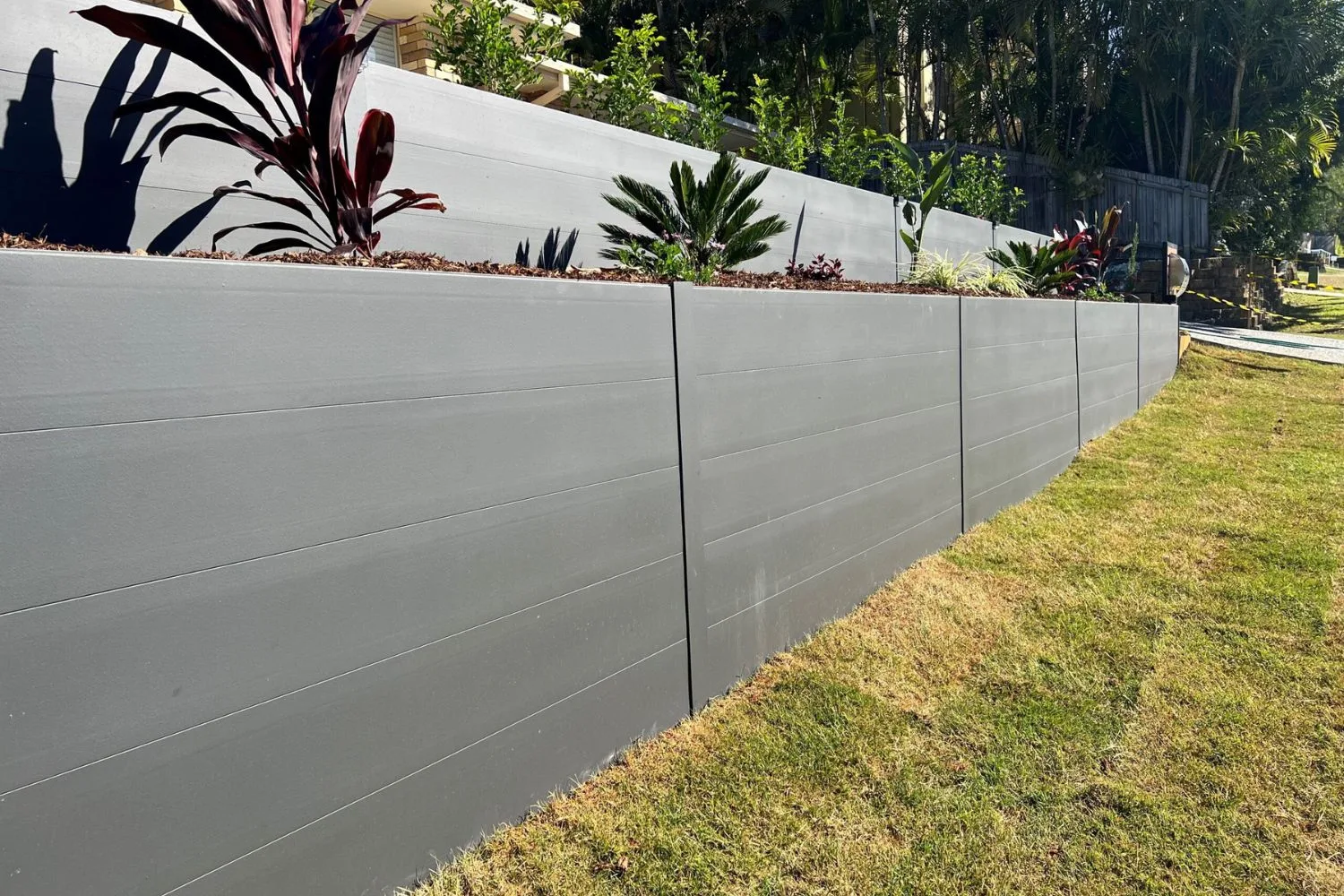 Modern precast concrete panel retaining wall with a garden bed on top