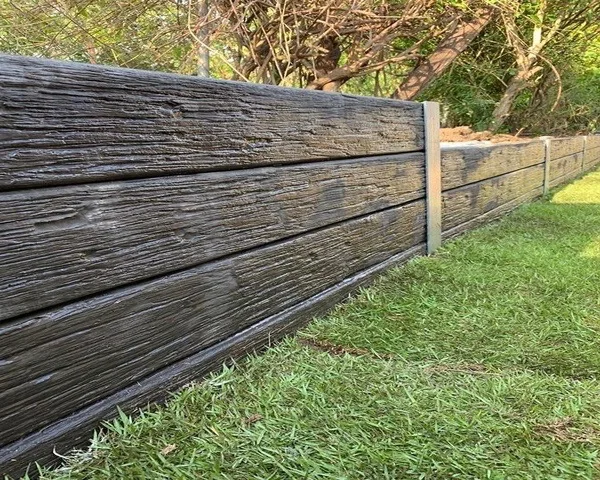 Timber-look concrete sleeper retaining wall along a lawn edge