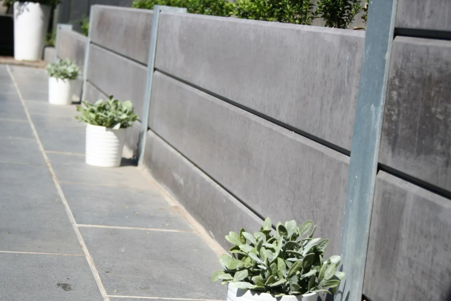 Modular concrete sleeper retaining wall with steel posts and planters