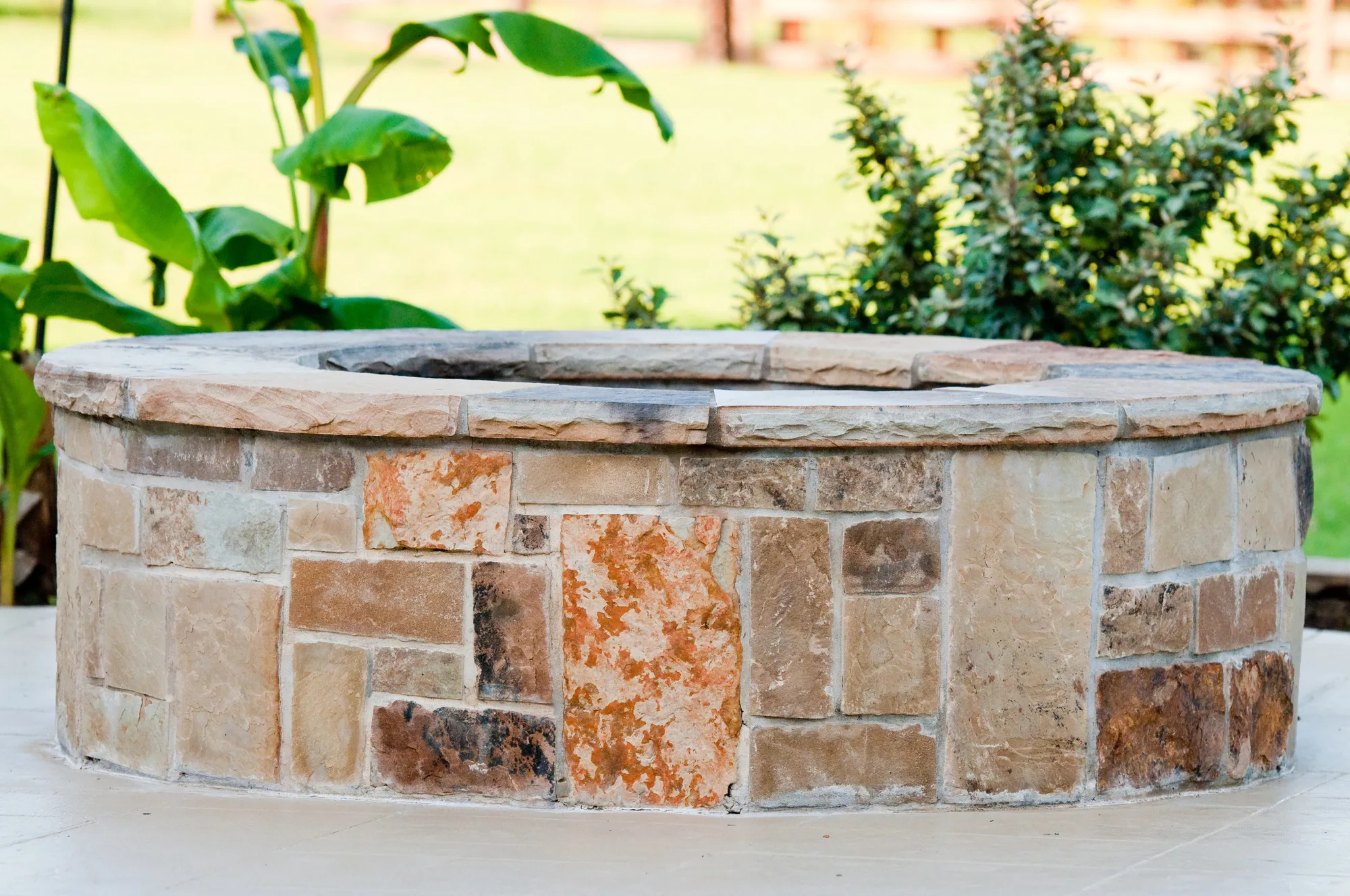Stone-clad firepit surround in a garden setting