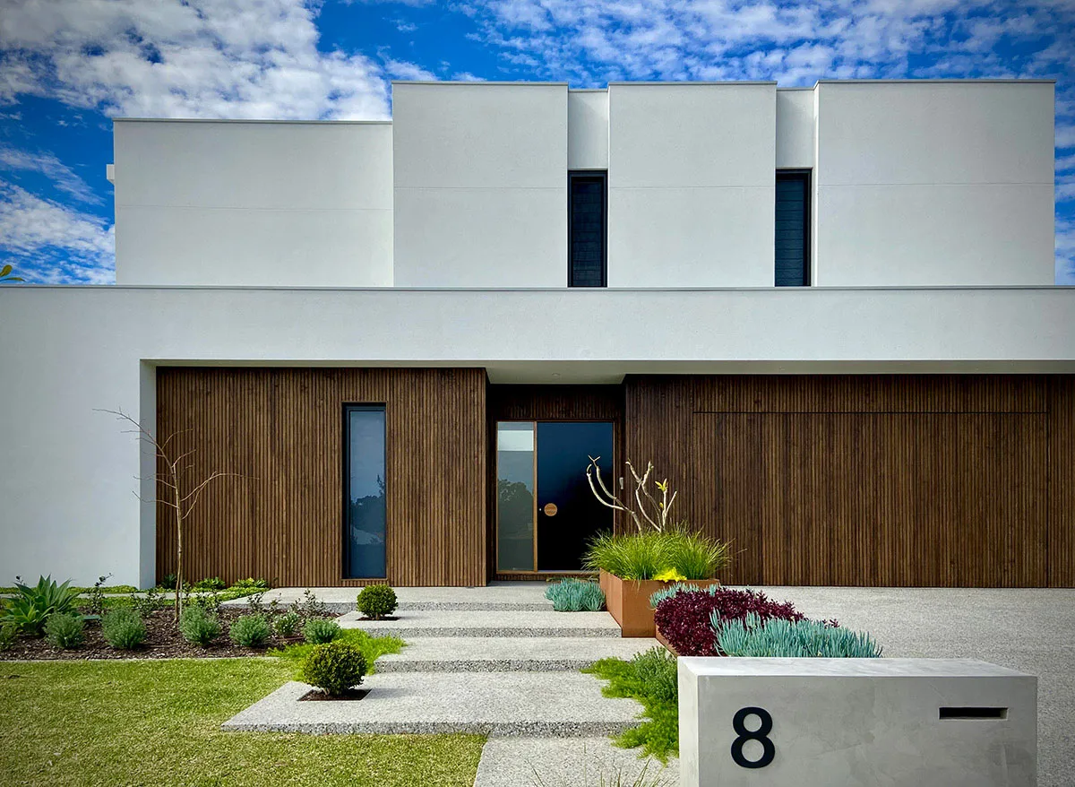 Modern home entrance with dark timber cladding and a succulent garden bed