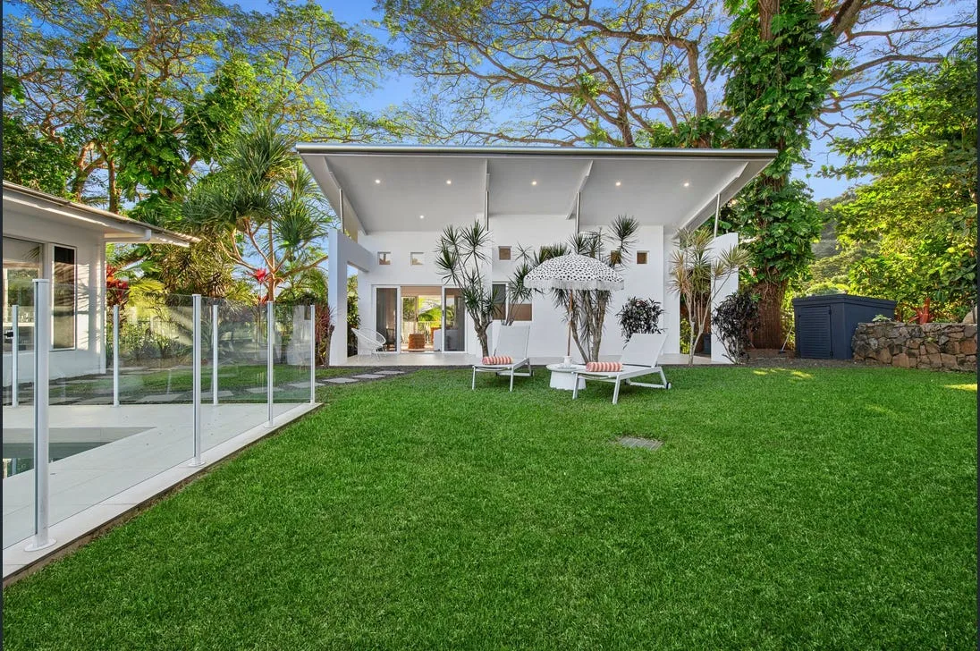 Gable-roofed alfresco area with an outdoor kitchen and dusk lighting