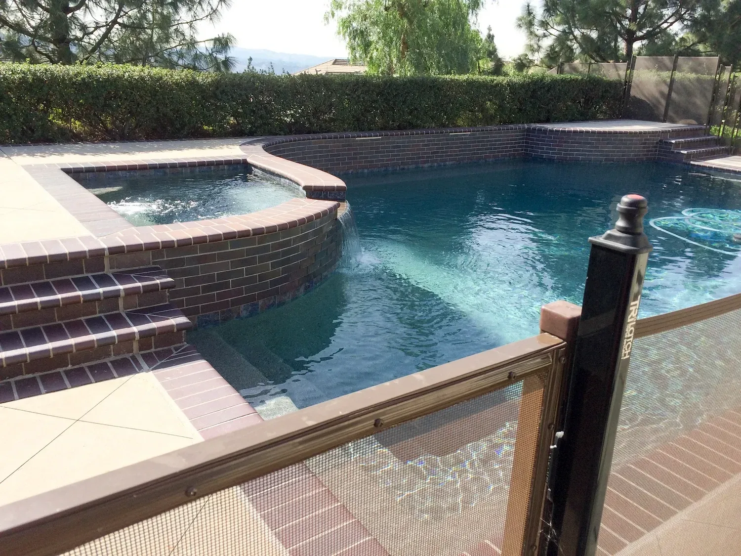 Raised brick spa with a waterfall edge flowing into a pool