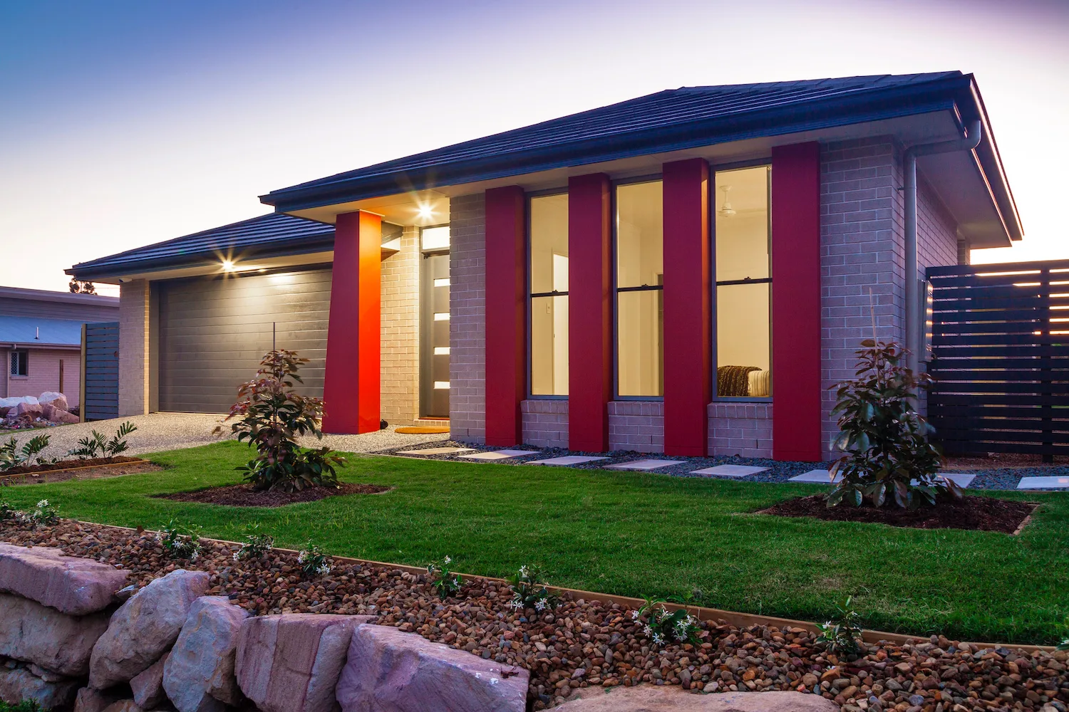 Brick home with a feature garden bed and red architectural columns