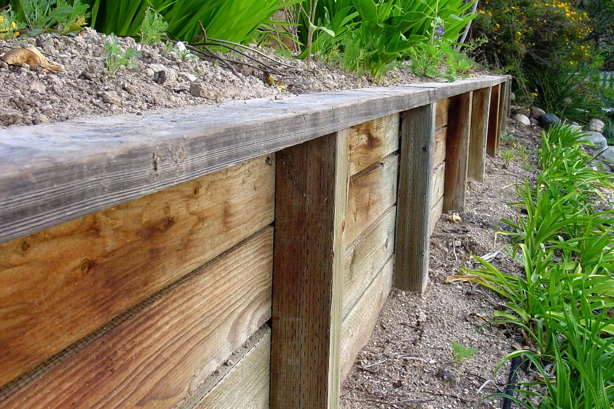 Raw timber sleeper retaining wall beside a garden bed
